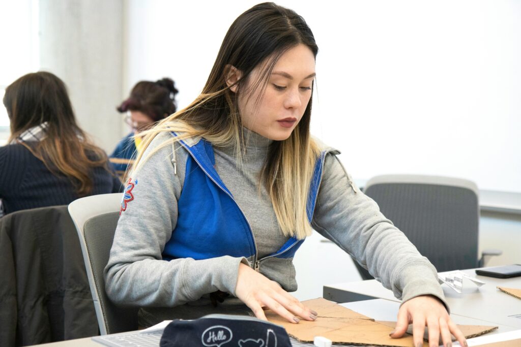 A college student concentrates on an art project in a classroom setting, showcasing a typical day at university.